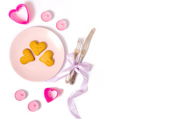 Obraz na płótnie Canvas pink plate, candles, romantic dinner, heart shaped cookies, knife and fork isolated on white background, valentines day concept, flat lay