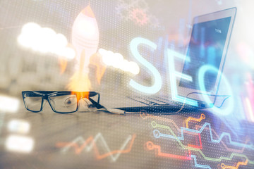 Multi exposure of table with computer and seo drawing hologram. Search optimization concept.