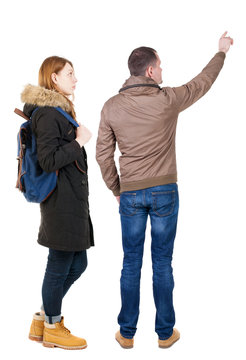 Back view of couple couple in winter jackets pointing.