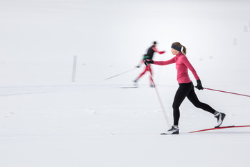 Cross-country skiing: young woman cross-country skiing on a winter day (motion blurred image)