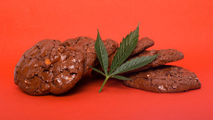 Obraz premium sweets with marijuana on red background. cannabis cookies and green leaf