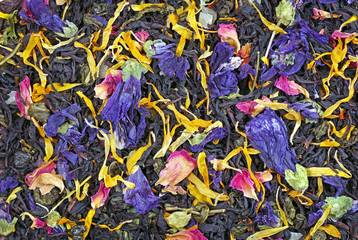 black blended tea with flower petals and slices of dried fruit texture background