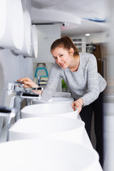 Smiling female buyer choosing ceramic washbasin in store
