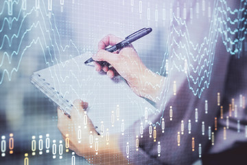 Multi exposure of hands making notes with forex chart huds. Stock market concept.