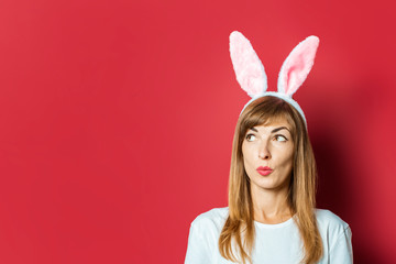 Young beautiful woman with rabbit ears on a pink background. Easter concept