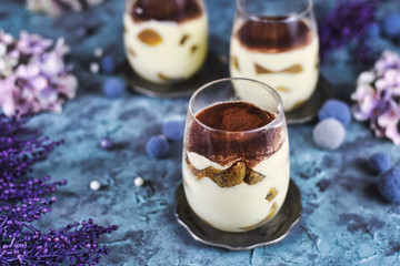 Homemade coffee flavoured layered Italian mascarpone cheese Tiramisu dessert topped with cocoa in glasses