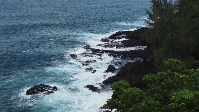 HD 120fps Hawaii Kauai overhead view of waves crashing on rocky shoreline covering nearby rocks, slight left to right pan