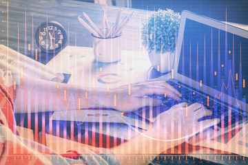 Double exposure of stock graph with businessman typing on computer in office on background. Concept of hard work.