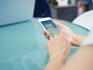 外でスマートフォンを操作する女性