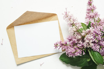Lilac flowers and envelope on white background. Spring flowers. Top view, flat lay. Copy space. - Image