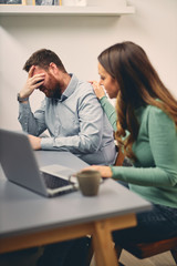 Young male having headache at work. His colleague trying to help. 