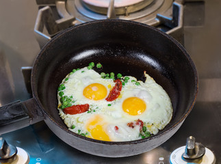 Eggs fried with green pea in frying pan on stove