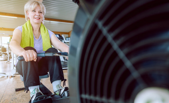 Senior Woman On The Rowing Machine In A Fitness Gym