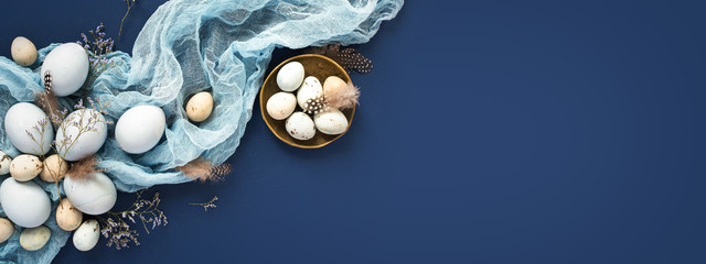 Easter banner with painted eggs and napkin on dark blue backround. Top view, flat lay with copy space.