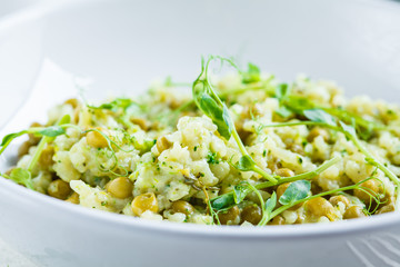 Green risotto with broccoli, green peas and sprouts in white plate. Healthy vegan food concept.