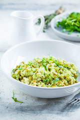 Green risotto with broccoli, green peas and sprouts in white plate. Healthy vegan food concept.