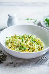 Green risotto with broccoli, green peas and sprouts in white plate. Healthy vegan food concept.