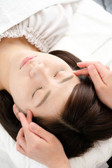 Fototapeta premium 鍼灸院でこめかみの指圧を受ける女性