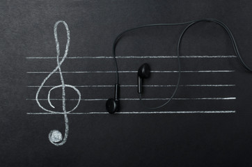 Top view of g-clef and earphones as symbol of notes on the staff. Concept of digitization of music