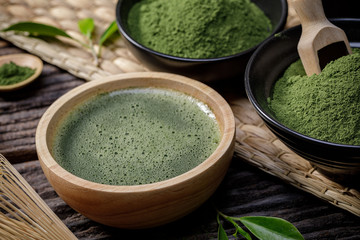 Japanese organic matcha green tea powder in bowl with wire whisk and green tea leaf on wooden background, Organic product from the nature for healthy with traditional style