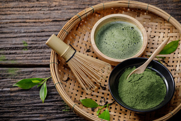 Japanese organic matcha green tea powder in bowl with wire whisk and green tea leaf on wooden background, Organic product from the nature for healthy with traditional style