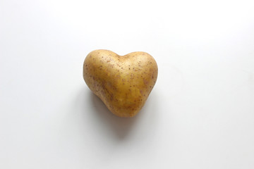 Ugly potato in the heart shape on a gray background. Funny, unnormal vegetable or food waste...