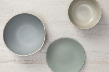 Group of empty blank ceramic round bowls and plates on white stone blackground, Top view of traditional handcrafted kitchenware concept