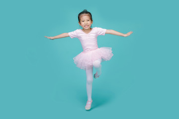 Beautiful smiling Asian little girl in a pink suit is dancing a ballet at school, empty space in...