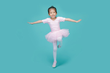 Beautiful smiling Asian little girl in a pink suit is dancing a ballet at school, empty space in studio shot isolated on colorful blue background