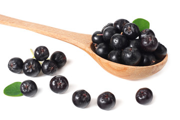 Chokeberry in wooden spoon isolated on white background. Black aronia