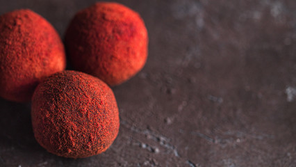 Red homemade truffle coated dry beet powder on dark background. Copy space right for text or...