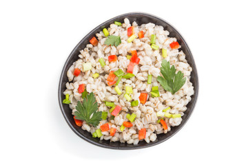 Pearl barley porridge with vegetables in blue ceramic bowl isolated on white background. Top view, close up.