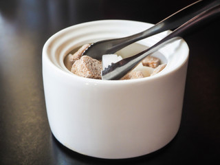 Sugar-basin with cubes of white and brown sugar on black background