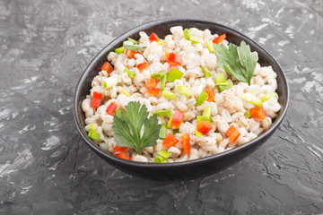 Pearl barley porridge with vegetables in blue ceramic bowl.  side view, close up.