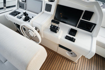 Steering wheel in control deck with monitors for an expensive luxury boat. Detail of the interior of a yacht. © galaganov