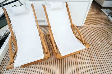 Obraz na płótnie Canvas Two wooden luxury deck chair chairs on the deck of a yacht.