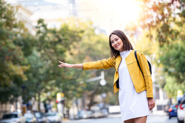 Young Asian woman hailing a taxi ride. Beautiful charming woman hailing a taxi cab in the street. Businesswoman trying to hail a cab in the city. Tourist woman hailing a taxi © Graphicroyalty