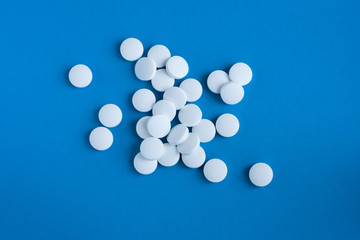 White pills on a blue background. Medicine and health