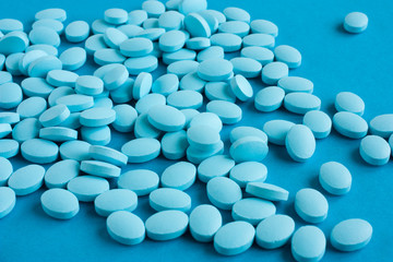 Light blue pills on a blue background. Medicine and health