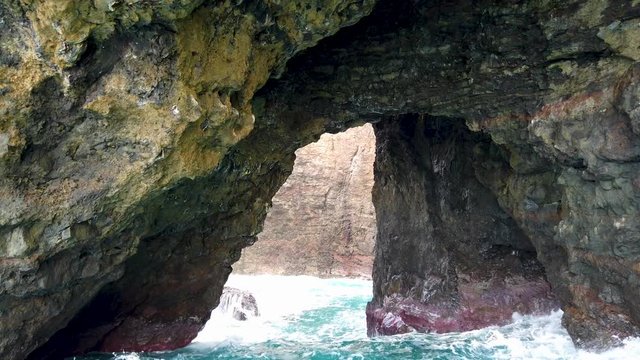 4K Hawaii Kauai Boating on ocean floating toward rocky arch tunnel