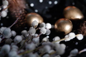 Easter holiday, composition on a dark background. Golden eggs and feathers of partridge in black...