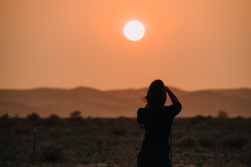 woman taking photos of sunset with camera