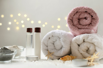 Obraz na płótnie Canvas Spa concept. Towels, bottles of oil and moisturizing cream, clay for body and face, sea salt and seashell, starfish
