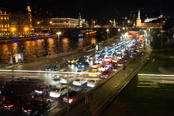 Fototapeta na wymiar Night traffic of cars in a big city. Evening Moscow. Light from headlights of cars and buildings. The movement of cars on the street.