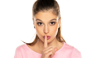 Fototapeta premium Portrait of young beautiful woman with finger on her lips