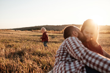 Happy Young Family Mom and Dad with Their Little Son Enjoying Summer Weekend Picnic Outside the City in the Field at Sunny Day Sunset, Vacation Time Concept