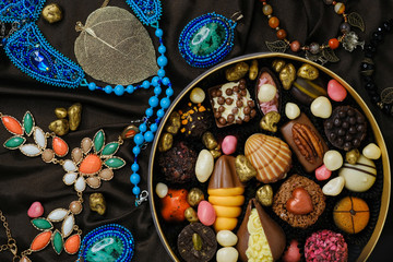 Handmade chocolate candies and sweets on background of jewelry and decorations.