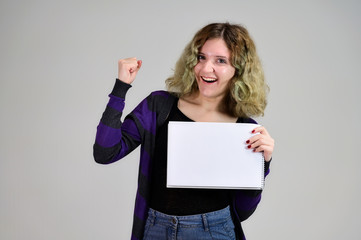 Naklejka premium Concept horizontal photo of a young woman with emotions in a dark jacket standing in front of the camera on a white background. Portrait of a student girl with a folder in her hands with fluffy hair.