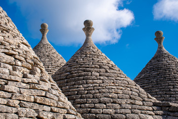 Fototapeta na wymiar Group of beautiful ancient Trulli, traditional old houses and old stone wall in Puglia, Italy, Europe