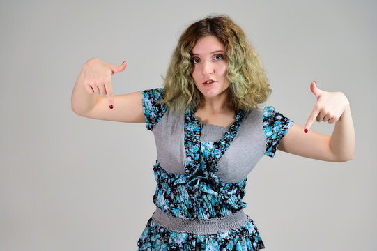 Portrait of a student girl with beautiful magnificent hair. Concept horizontal photo of a young woman with emotions in a turquoise dress stands in front of the camera on a white background.